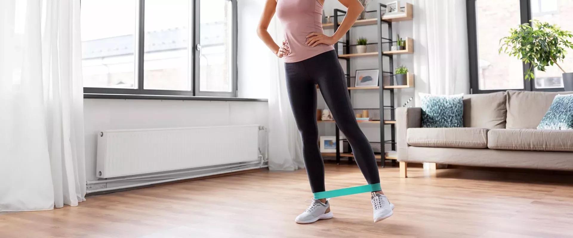 5 Tipps für das Training mit Trainingsbändern Bild einer Person mit einem über den Beinen befestigten Trainingsband