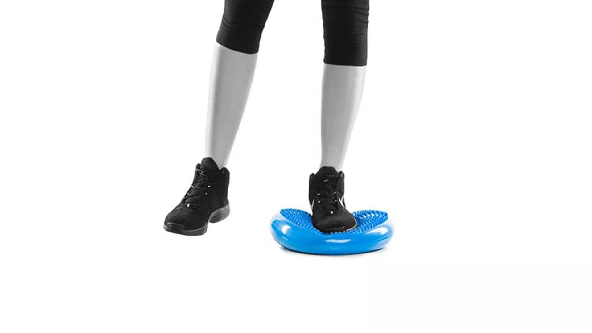 Übung 8: Einbeinstand auf Balancekissen Person, die mit einem Bein auf einem Balancekissen steht